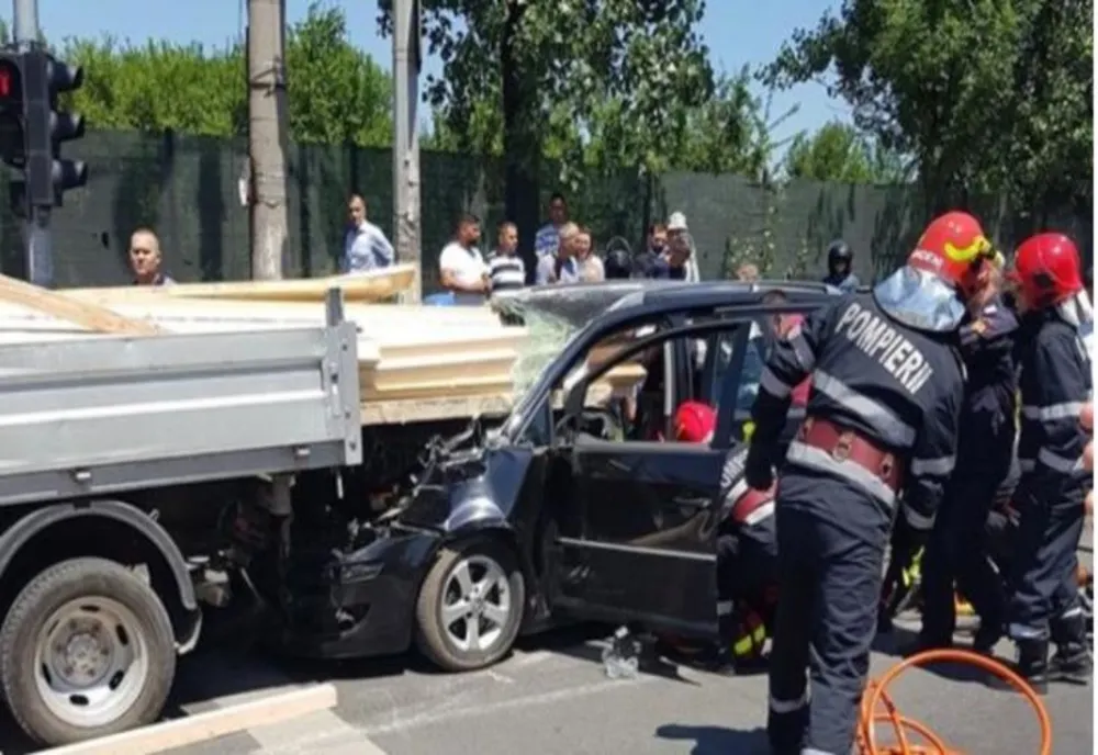 O mașină a intrat în plin într-o dubă încărcată cu lemne. Șoferul, rănit grav de lemnele intrate prin parbirz